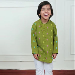 Niño pequeño con kurta verde estampada y pijama blanco, sonriendo y riendo mientras se encuentra en el interior de una casa con un atuendo tradicional. - Product Image 1