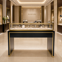 Vitrine de présentation de bijoux de luxe, cadre en acier inoxydable doré, base noire, verre trempé pour les détaillants de bijoux haut de gamme