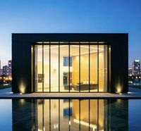 Villa minimaliste avec mur-rideau en verre et structure en acier, dotée d'un système d'éclairage nocturne