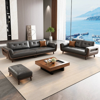 Canapé trois places en cuir pleine fleur gris foncé, dossier capitonné à boutons carrés, accoudoirs en bois découpé, style minimaliste du milieu du siècle