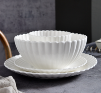 Servies van wit porseleinen kommen en borden met gegolfde rand, milieuvriendelijk, BPA-vrij, voedselveilig, met aangepast logo, modern design, geschikt voor salade en soep.