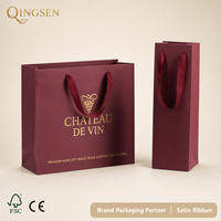 Sacs cadeaux pour vin en papier bordeaux mat personnalisés OEM, avec poignées en ruban satiné estampées à chaud or, durables et recyclables pour les boutiques