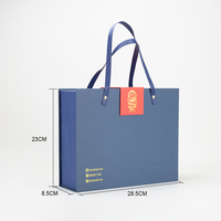 Boîte cadeau de Noël et du Nouvel An bleue, orange et rouge en papier couché avec pelliculage brillant et mat, gaufrage et estampage pour bougies