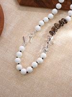 Collier unisexe tendance minimaliste en perles de corail blanc avec cristaux clairs et fumés noués sur un fil de laiton