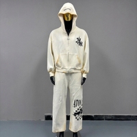 Ensemble de survêtement 2 pièces personnalisé à bords effilochés, comprenant un sweat à capuche court zippé et un pantalon de survêtement large, avec imprimé graphique gothique, style streetwear décontracté