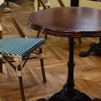 Table de bistrot vintage de style parisien, plateau rond en bois festonné avec base en fonte.