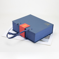 Boîte cadeau de Noël et du Nouvel An bleue, orange et rouge en papier couché avec pelliculage brillant et mat, gaufrage et estampage pour bougies