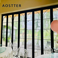 Porte pliante AOSTTER en aluminium finition noire minimaliste avec panneau de sécurité haute transparence et seuil encastré pour villa contemporaine
