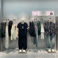 Boutiquede vêtements d'affairesélégants avecaffichage en métalnoir, cintres linéaires et unités de rangement à plusieurs niveaux
