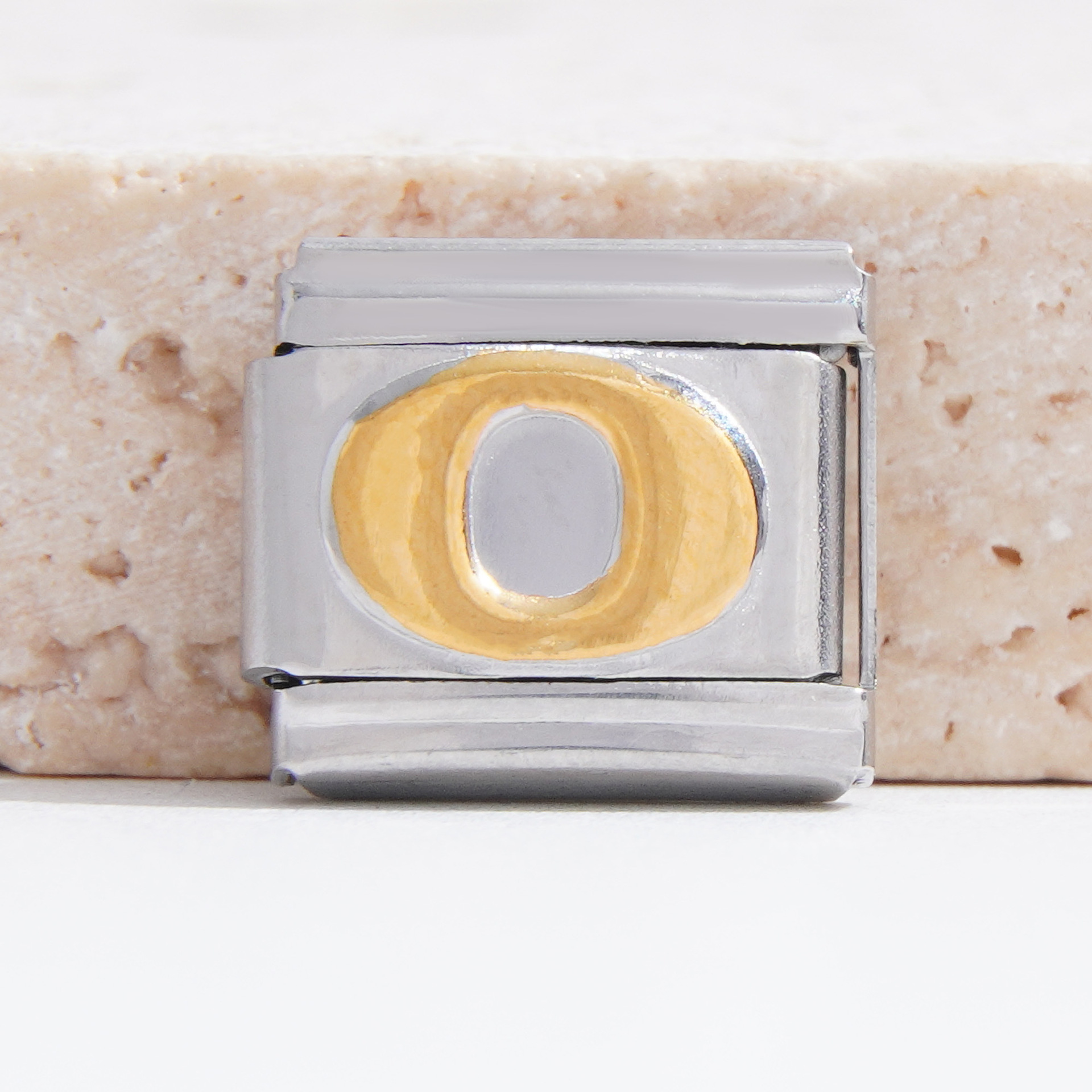 Base plateada con O dorada.