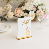 Numéros de table de mariage en acrylique blancs avec numéros sérigraphiés or et supports de présentation
