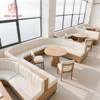 Ensemble de banquette moderne et confortable avec structure métallique incurvée et revêtement en cuir blanc, table ronde en bois pour restaurant ou café