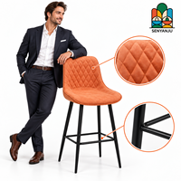 Tabouret de bar en cuir orange matelassé avec dossier en losanges, quatre pieds en métal noir, repose-pieds, hauteur de comptoir