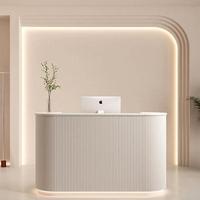 Comptoir de réception de salon de beauté incurvé en MDF blanc avec logo gravé personnalisé rétroéclairé par LED