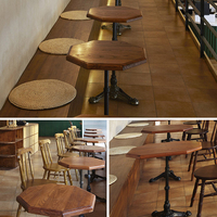 Table à manger octogonale en bois avec piétement en fonte et chaises à dossier en tige pour ensemble de restaurant ou café rustique