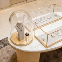 Table de présentation de bijoux de luxe avec plateau en marbre et pieds cylindriques en or brossé |   Vitrines en verre éclairées par LED avec socles en forme de dôme |   Personnalisable
