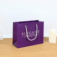 Sacs en papier noir enduit avec logo blanc imprimé sur mesure haut de gamme pour l'emballage de cadeaux et les soins personnels