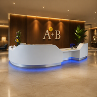 Bureau de réception incurvé personnalisé en Corian blanc avec base en acier inoxydable argenté pour hall d'hôtel
