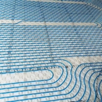Cinq raccords fixes du système de climatisation à source géothermique soutiennent uniformément les conduites de chauffage sous le plancher.