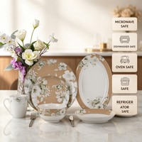 Service de table en porcelaine Bone China avec bordure dorée perlée, motif fleur blanche et feuille verte, comprenant assiette, bol, tasse, soucoupe, mug et plat de présentation