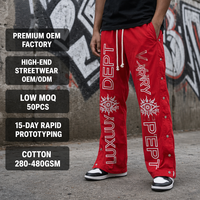 Pantalon de survêtement large personnalisé rouge en nylon résistant à l'eau avec broderie et boutons-pression latéraux détachables pour le streetwear urbain