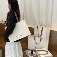 Sac fourre-tout en papier biodégradable blanc crème de luxe avec logo personnalisé, laminage mat, large ruban pour boutique de vêtements et de chaussures