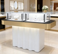 Table de présentation VIP pour bijoux de luxe avec éclairage LED, cadre en métal doré, vitrine en verre et base ondulée, personnalisable pour les magasins de bijoux