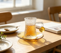 Ensemble de tasses à café en verre borosilicate martelé, forme sablier texturée, avec poignée boule ambrée, capacité 120 ml, et soucoupe à thé