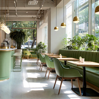 Ensemble de meubles pour café, restaurant, salon de thé : fauteuils en cuir vert avec pieds en bois, tables rectangulaires en bois et canapé banquette vert.