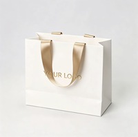Sac cadeau en papier blanc de luxe personnalisé avec poignée en ruban de satin doré, logo estampé à chaud pour l'emballage de boutiques et de commerces de détail
