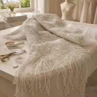 Tissu en dentelle de haute couture lourdement perlé avec franges en boucle motif feuille d'argent sur tulle ivoire pour robe de mariée et robe de soirée