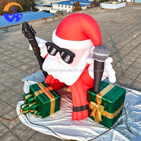 Arche gonflable géante Père Noël rockeur avec guitare, microphone et boîtes cadeaux pour l'entrée de centre commercial, la cour ou les événements de Noël
