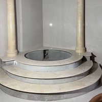 Escalier circulaire en marbre beige, marches courbes en pierre, plateforme ronde en marbre pour spa, supportant une colonne romaine pour l'intérieur d'une résidence.