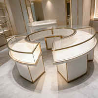 Vitrine de présentation de bijoux en verre incurvé en forme de C, modulaire, blanche brillante avec finition en métal doré, vitrine LED pour boutique de détail