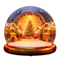 Globe de neige gonflable géant transparent pour Noël, avec fond personnalisé et base rouge, idéal pour l'affichage en centre commercial, la location pour événements et la décoration de fêtes