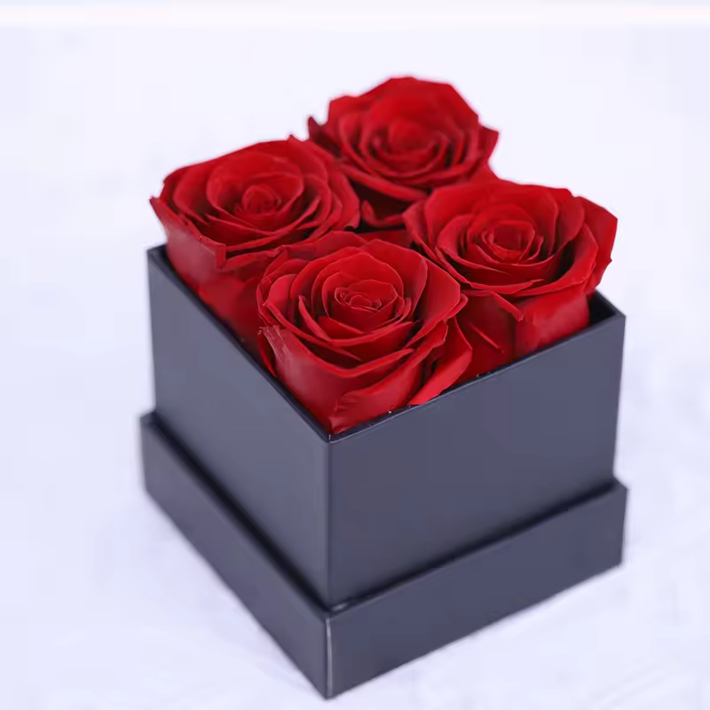 4 roses rouges dans une boîte carrée noire