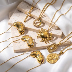 JUSNOVA Collier hypoallergénique en acier inoxydable plaqué or PVD 18K, résistant à l'eau et inaltérable, avec pendentifs croix, crabe, œil porte-bonheur et médaille en forme de haricot - Product Image 1