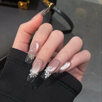 Faux ongles en acrylique rose nude effet œil de chat avec bouts français transparents, fleurs blanches et accents de strass pour un style minimaliste et nuptial