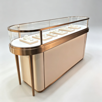 Comptoir de présentation de bijoux en verre incurvé, cadre en métal rose doré, vitrine aux coins arrondis avec éclairage LED chaud intégré, logo personnalisé