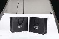 Sac fourre-tout en papier noir gaufré motif croco, avec logo personnalisé en feuille d'argent et poignée en cordon, idéal pour le commerce de détail haut de gamme et les cadeaux.