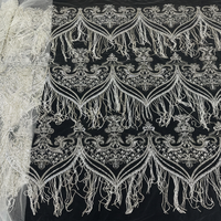 Tissu en dentelle de haute couture lourdement perlé avec franges en boucle motif feuille d'argent sur tulle ivoire pour robe de mariée et robe de soirée