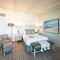 Ensemble de mobilier de chambre d'hôtel moderne pour complexe balnéaire : Lit avec tête de lit en bois blanc vieilli, Table de chevet, Fauteuil en tissu, Ottoman