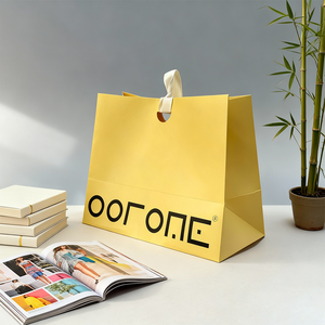 حقيبة ورقية صفراء زاهية بخط أسود جريء، تتميز بمقابض بيضاء متينة، تم التقاطها في نمط حياة بسيط - Product Image 5