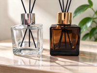 Flacon diffuseur de parfum carré de luxe de 50 ml, disponible en transparent et ambre, avec bouchons et bouchons intérieurs dorés et argentés.