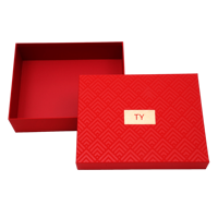 Boîte cadeau rigide à motif gaufré rouge festif avec étiquette dorée pour l'emballage de coffrets de soins de la peau de luxe