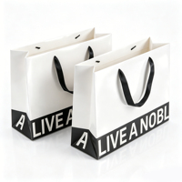 Sac cadeau en papier blanc minimaliste OEM/ODM avec poignées en ruban et typographie noire audacieuse pour la promotion d'emballages de marques de luxe modernes