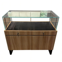 Comptoir d'exposition en verre trempé avec cadre noir mat, éclairage LED, intérieur blanc, base en bois de noyer avec tiroirs et serrures pour lunettes