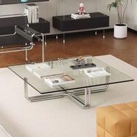 Un bureau à domicile avec une table basse carrée moderne et des meubles de salon transparents avec verre trempé et cadres métalliques