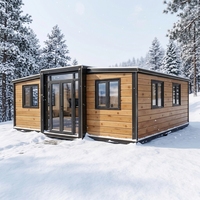 Maison conteneur moderne extensible 2 chambres, revêtement en bois clair, cadre noir, porte vitrée, vue sur la neige, respirante, garantie 1 an