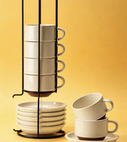 Ensemble élégant et tendance de tasses et soucoupes en céramique blanche, avec support métallique pour l'affichage, idéal pour la table à manger domestique et les scénarios de service du café et du thé.